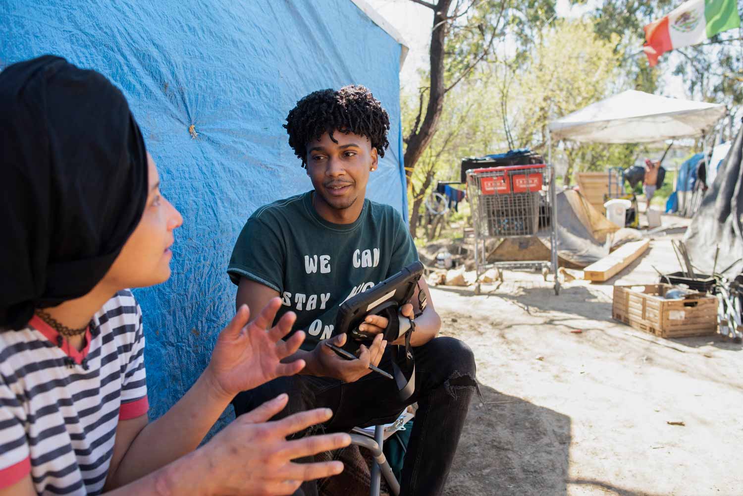 An African-American researcher interviews a woman at a homeless encampment.