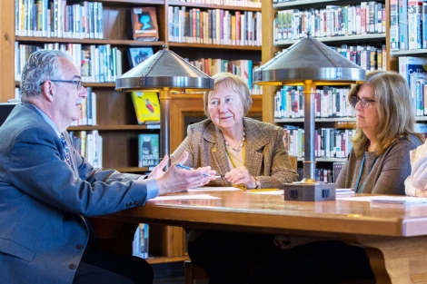 3 people discuss around a table at the library