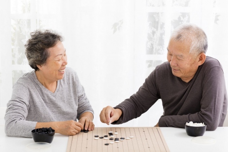 Asian elderly man and woman playing backgammon