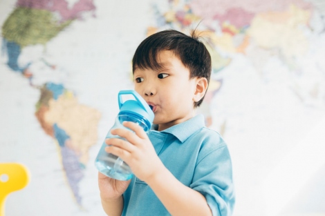 stock image of boy drinking from a water bottle at school