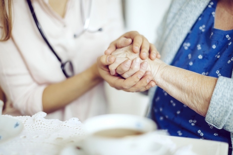 elderly woman holding hands with doctor