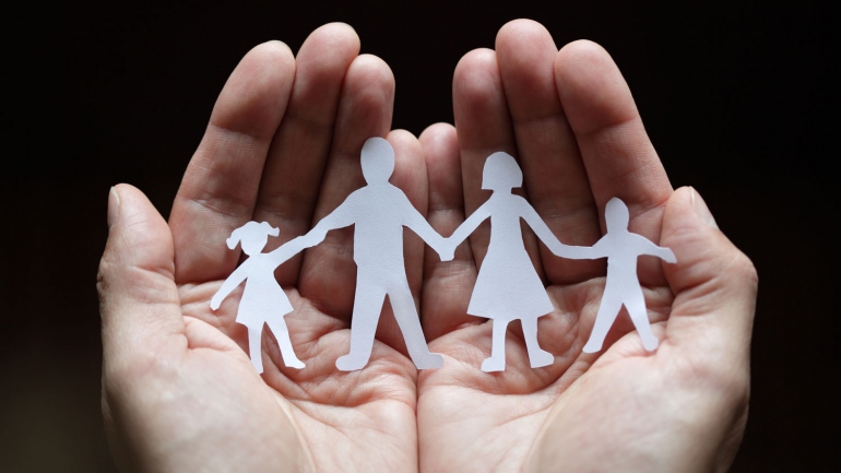 stock image of hands holding a paper cutout of a family