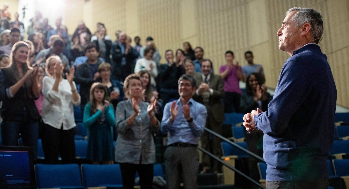 David Wofsy stands in front of a clapping audience at Cole Hall during the Last Lecture event