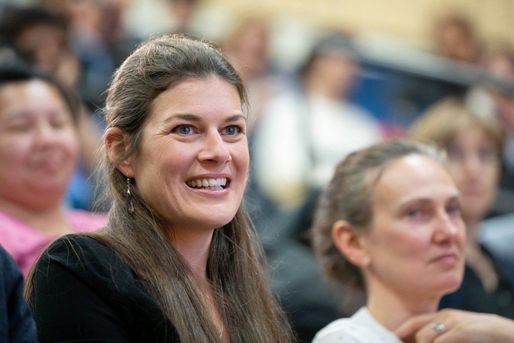 a woman smiles while listening to David Wofsy deliver the Last Lecture in Cole Hall