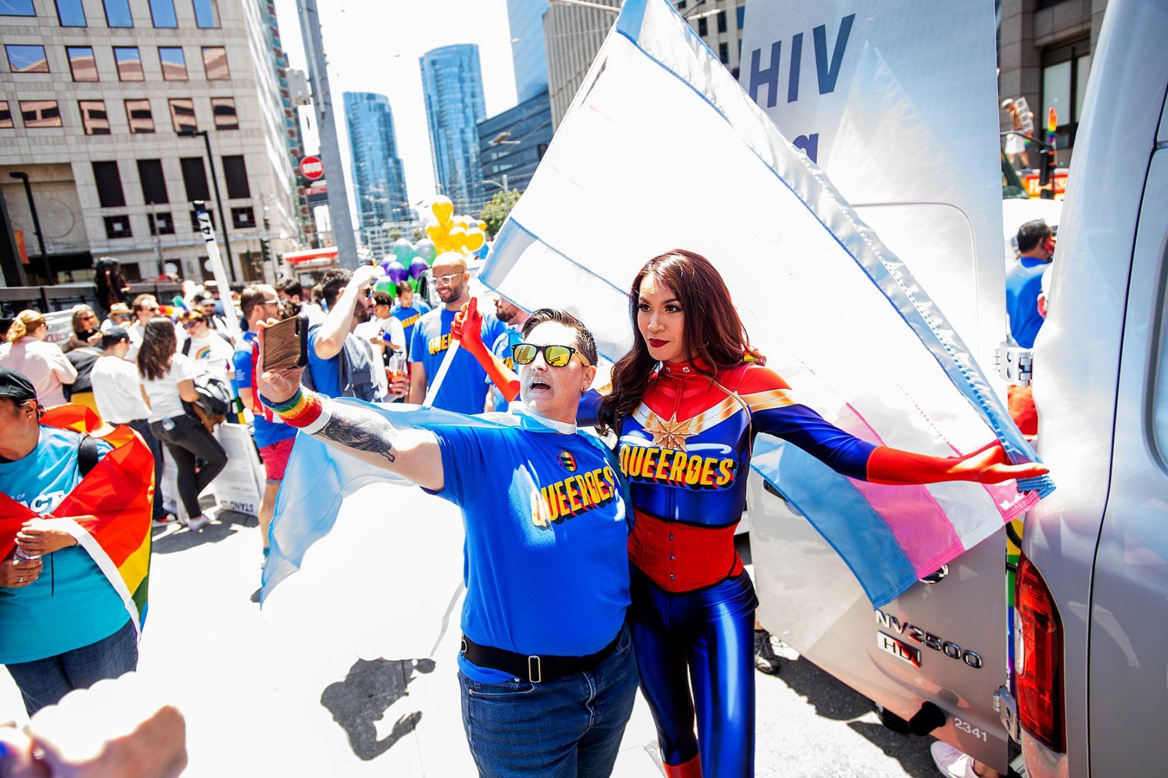 two people pose in outfits that say "Queeroes"