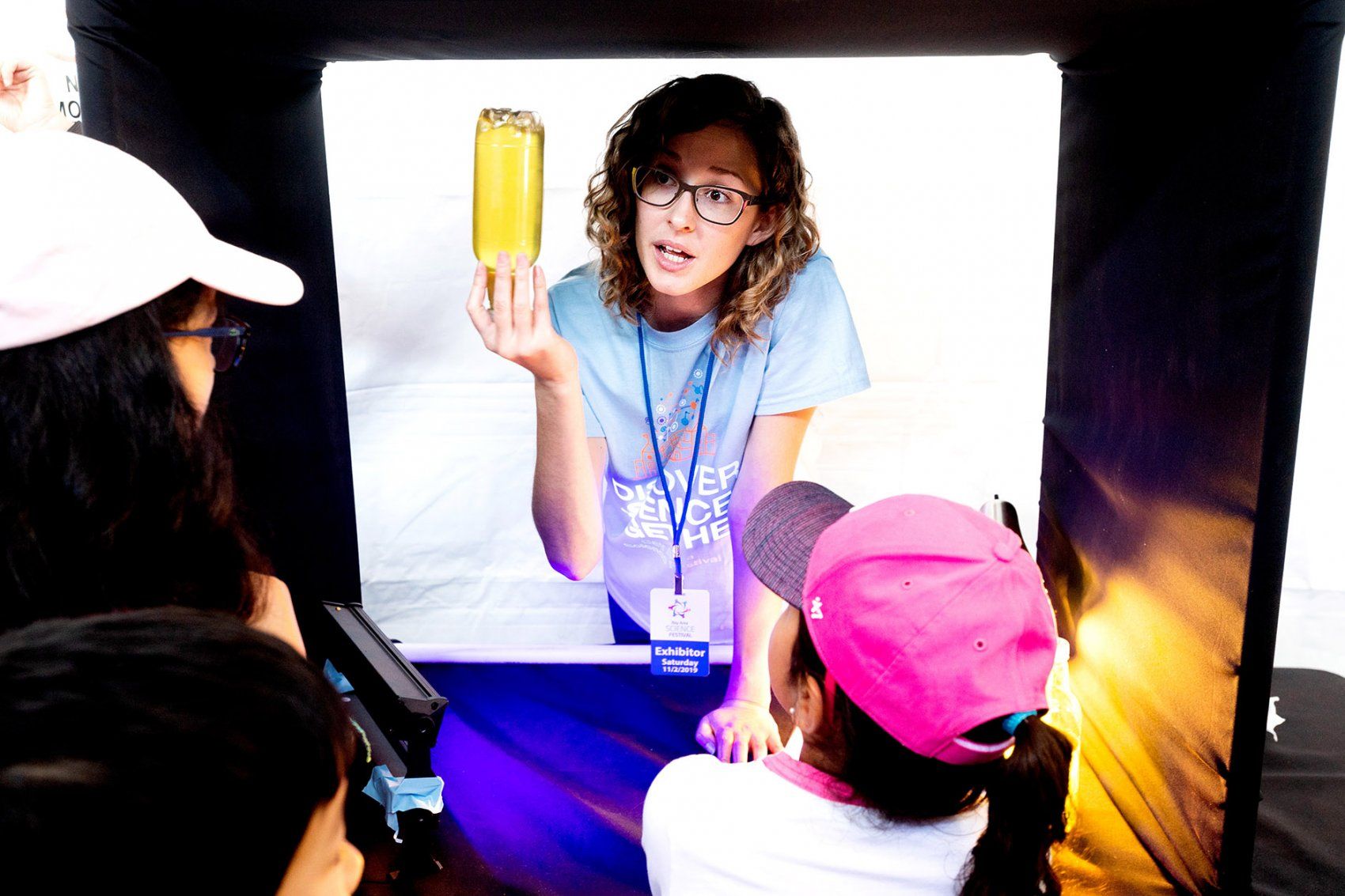 a woman holds a glowing bottle while she talks with children