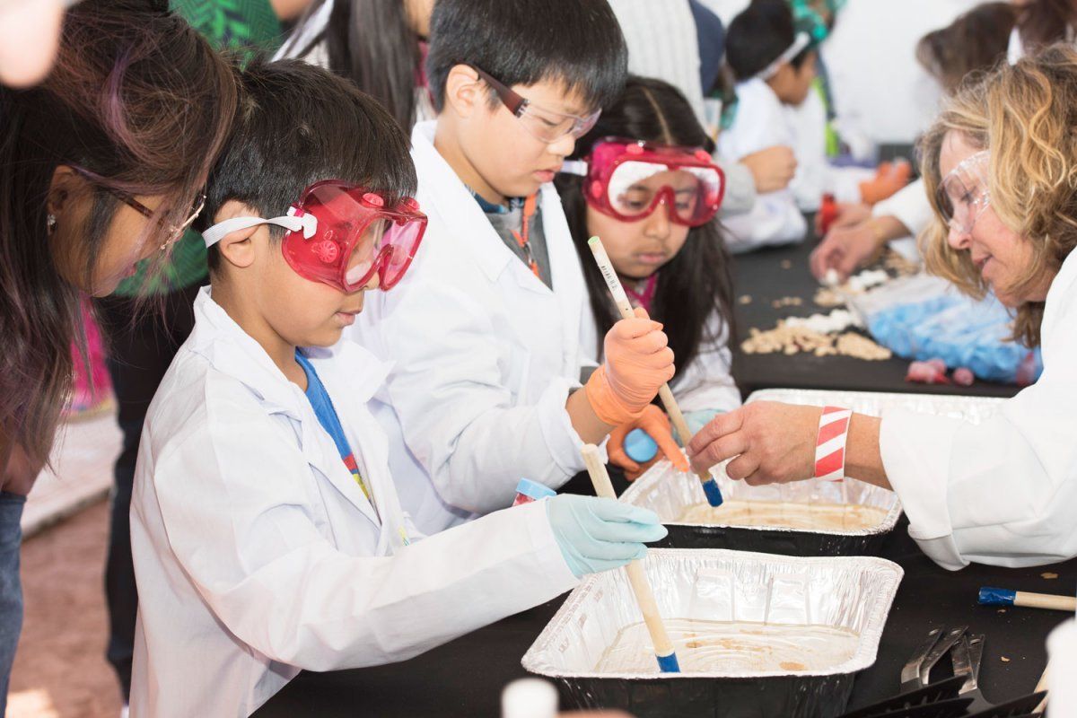 Children in lab coats and goggles conduct experiments