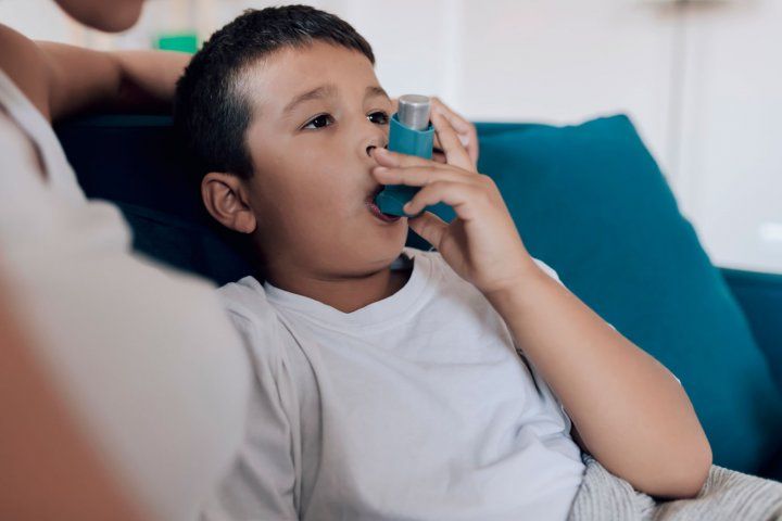 Child sitting on couch using an inhaler