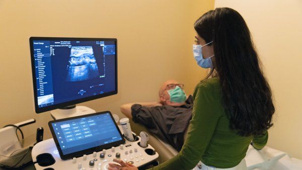 Joe Bojanowski lays on an examination table as Dr. Rishika Chugh examines his intestines through an ultrasound.