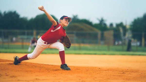 A young boy pitches a baseball during a baseball match.