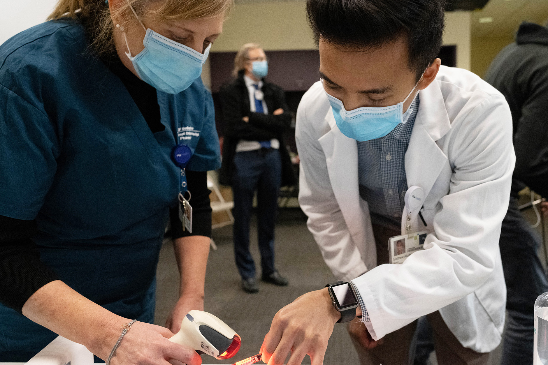 woman scans a barcode on a COVID-19 vaccination shot held by a man