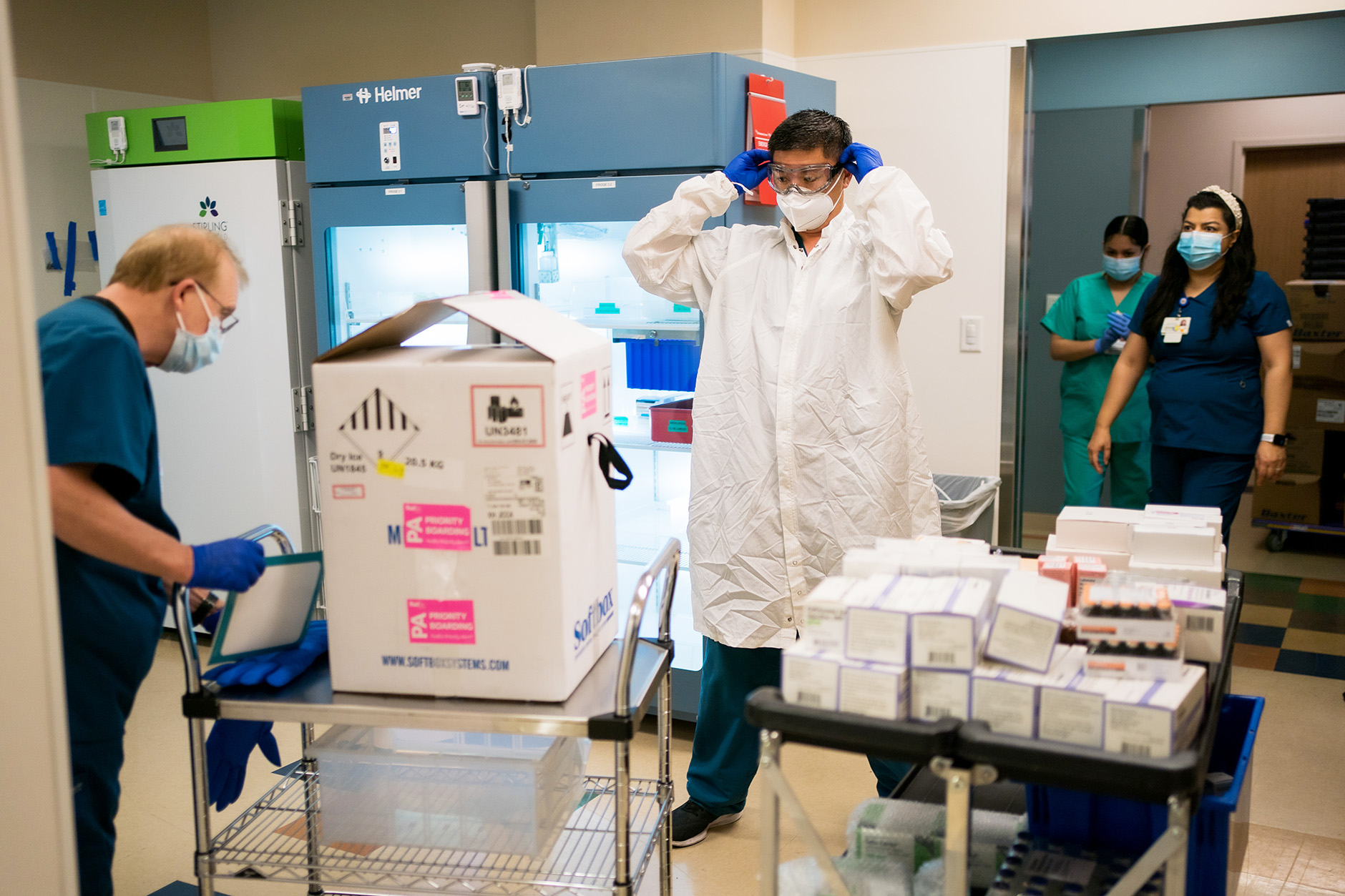 worker in goggles gets ready to open box with vaccine in it