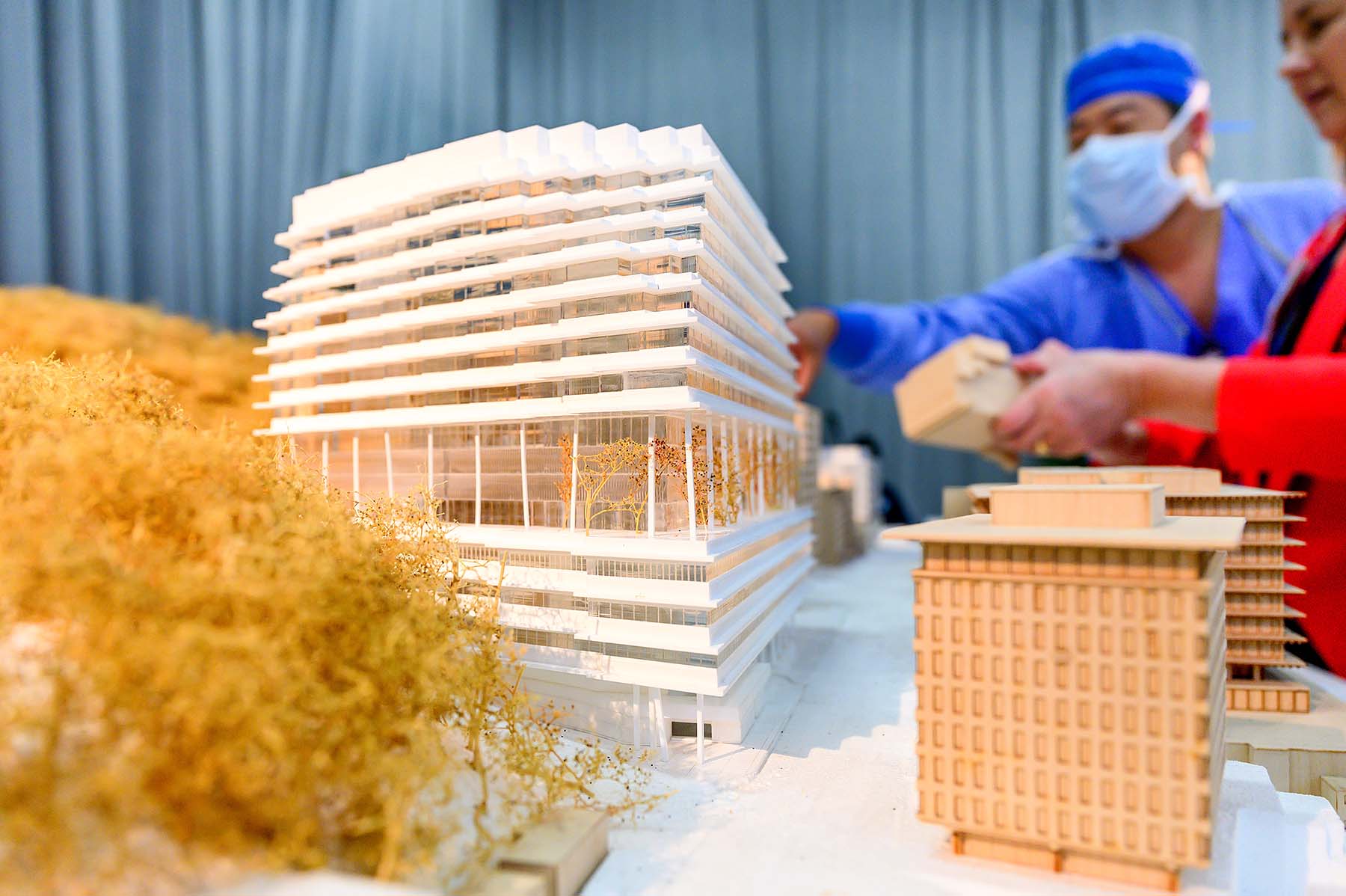 Visitors interact with a scale model of the new hospital building, complete with small trees against Mount Sutro.