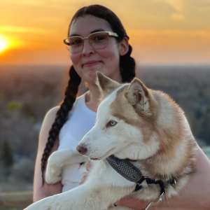 Luz holds hugs a dog above the city at sunset