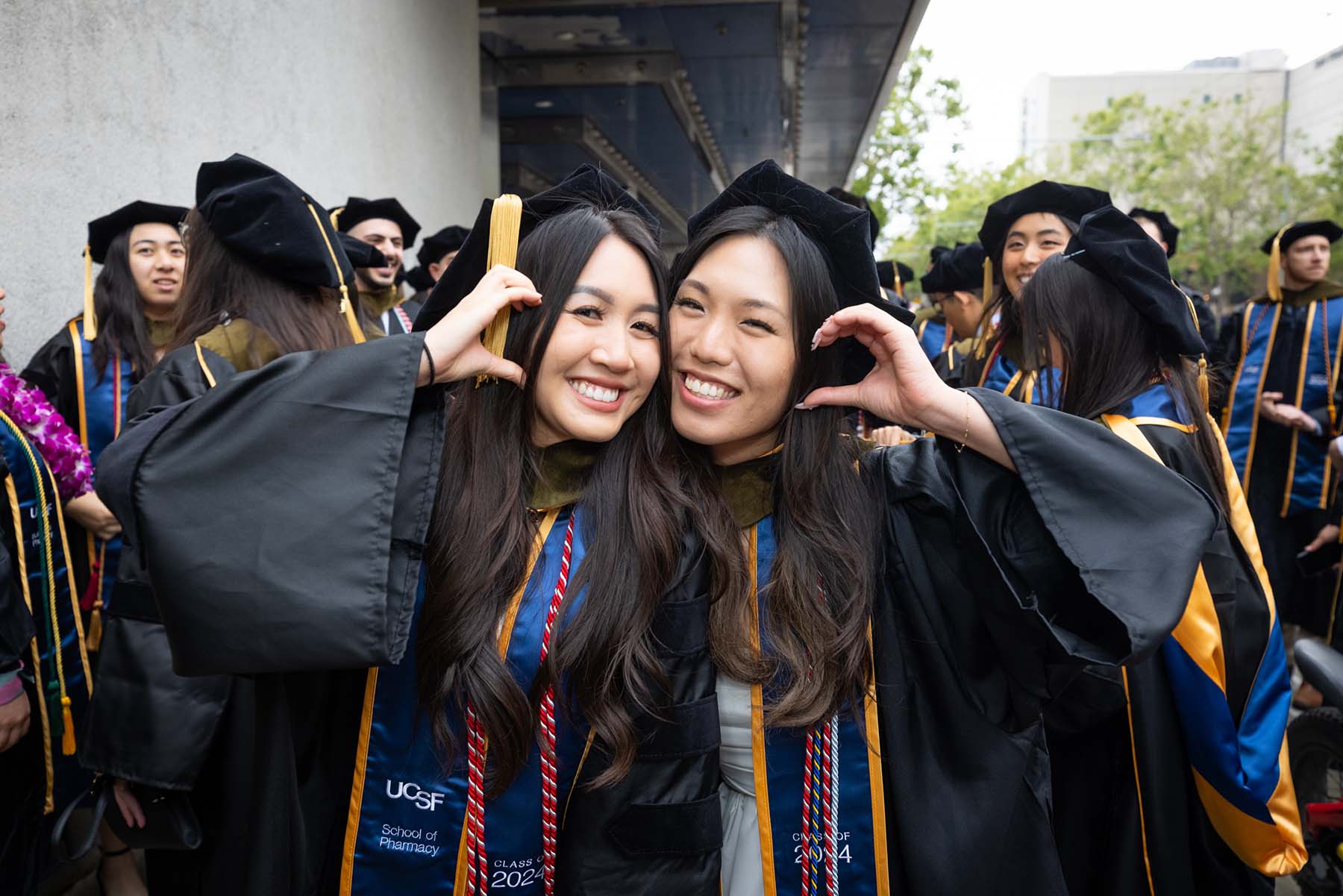 Two new Pharmacy grads stand outside the commencement hall.