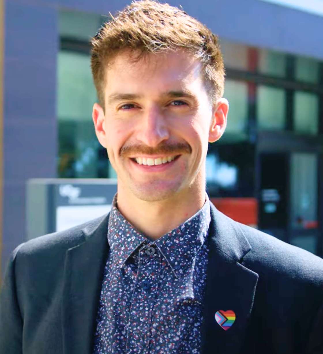 Kyle Lakatos poses wearing a queer pin