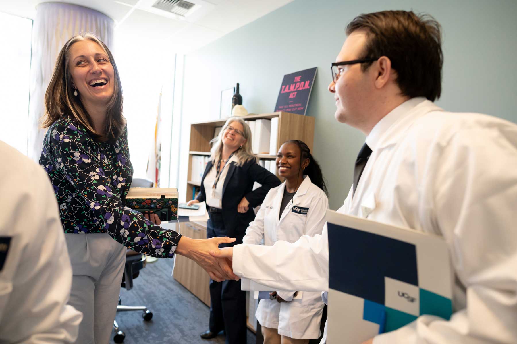Legislaitve aide Candace Cotton smiles as she shakes hands with UCSF dental student Brice Gentry.