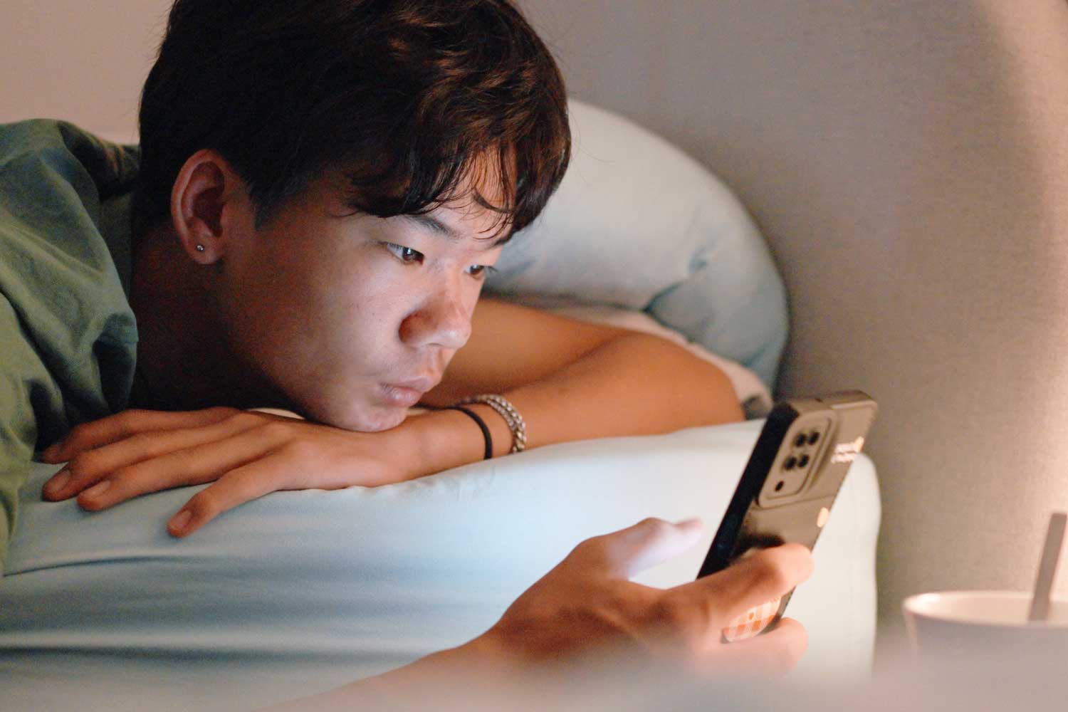 A teenage boy looking at his phone at night.