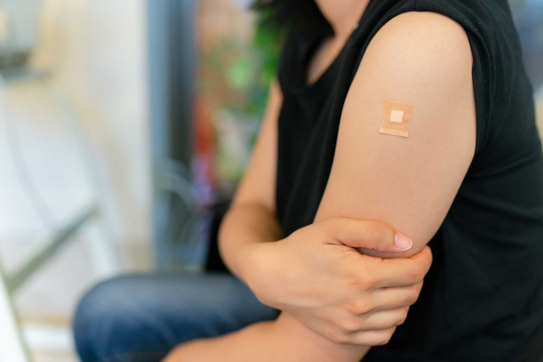 A woman with a bandaid on her arm after receiving a vaccine shot.