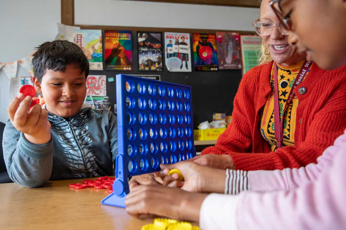 Two children play connect four with a social worker to help manage A D H D.