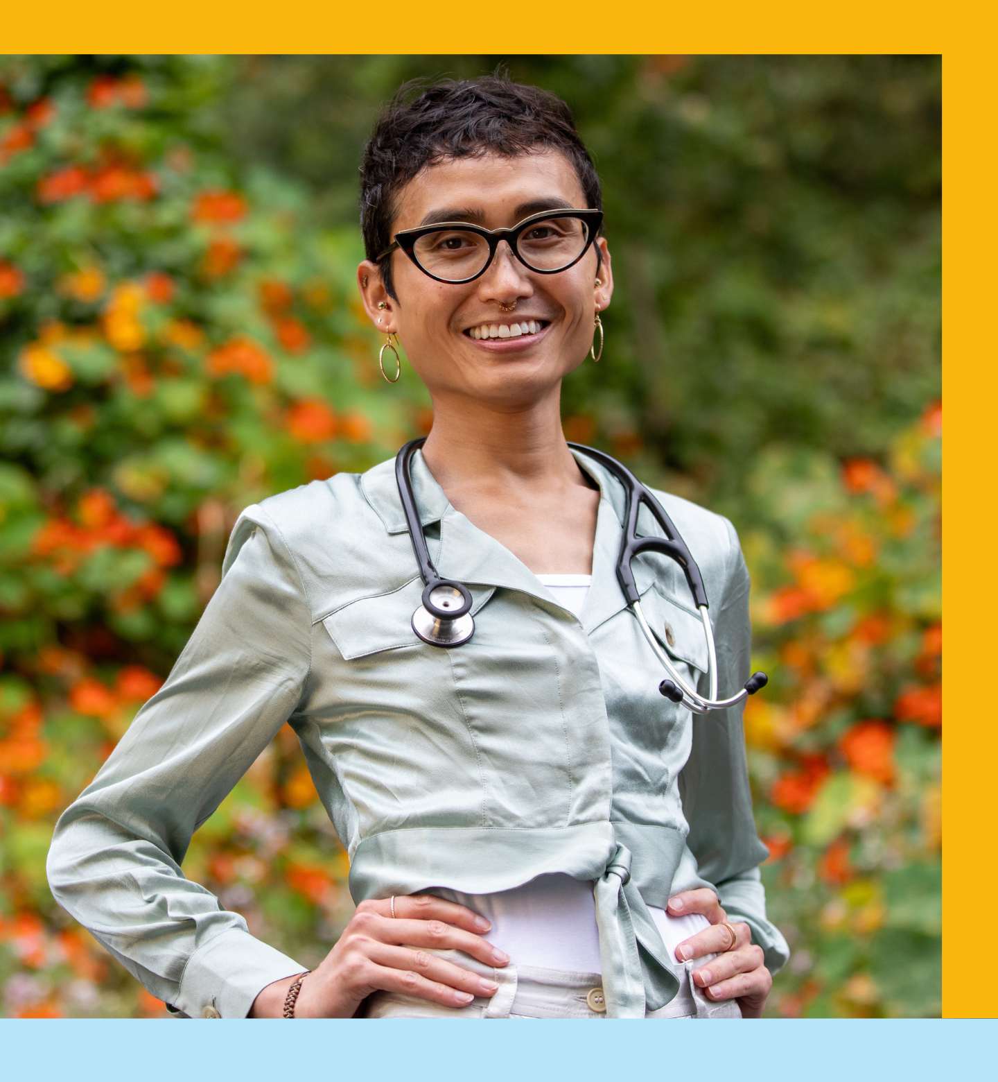 Sen wears stethoscope and poses in front of flowers.