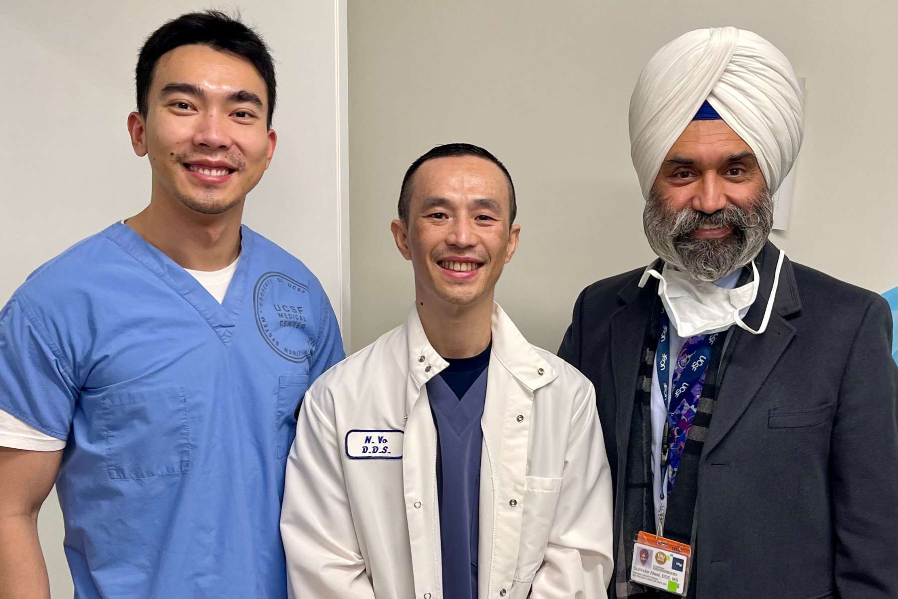 three men in dental gowns pose side by side