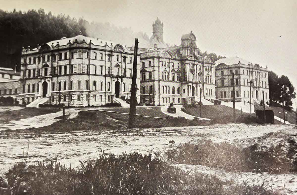 An old, sepia photo of the first building at Parnassus Heights, showing the natural sand dunes in the surrounding area.