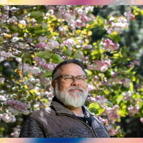 Jae Rouse smiles surrounded by pink flowers on tree.