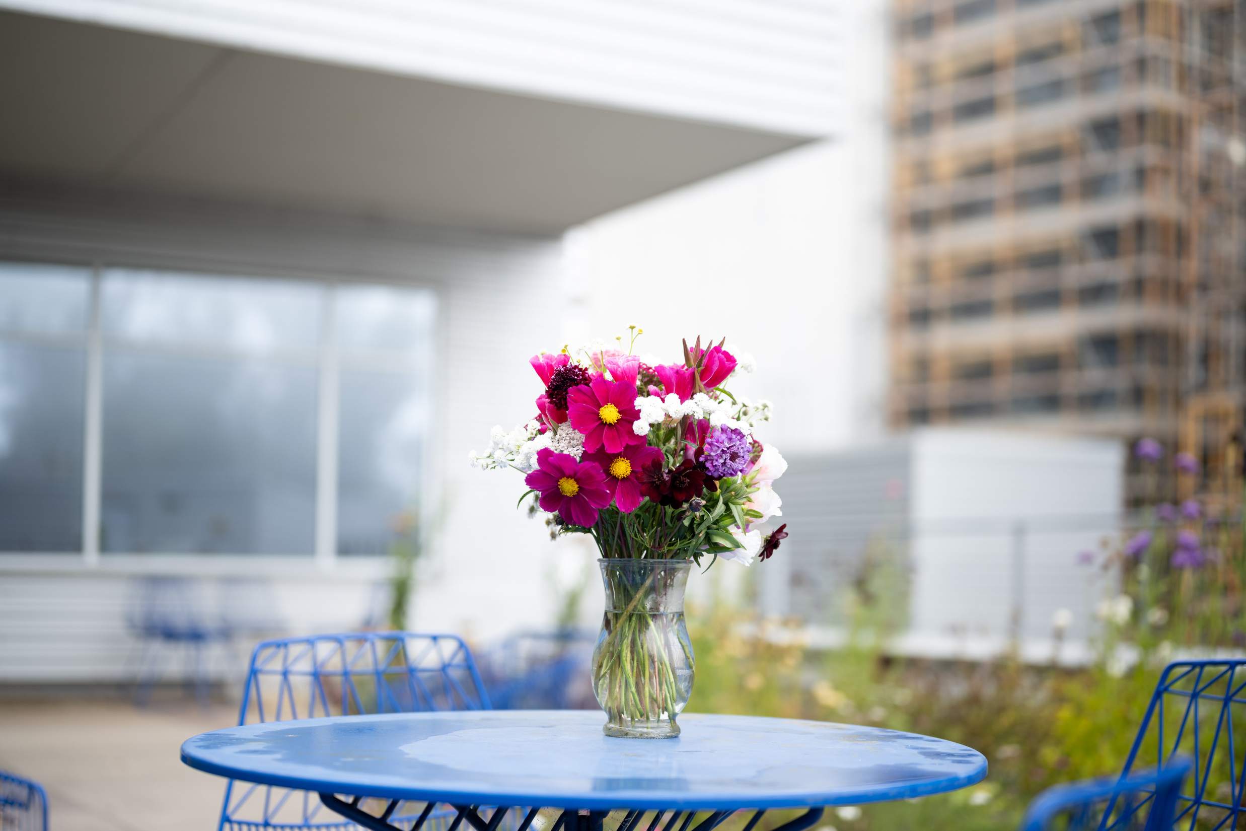 Wild flowers in a vase on blue outdoor garden table.