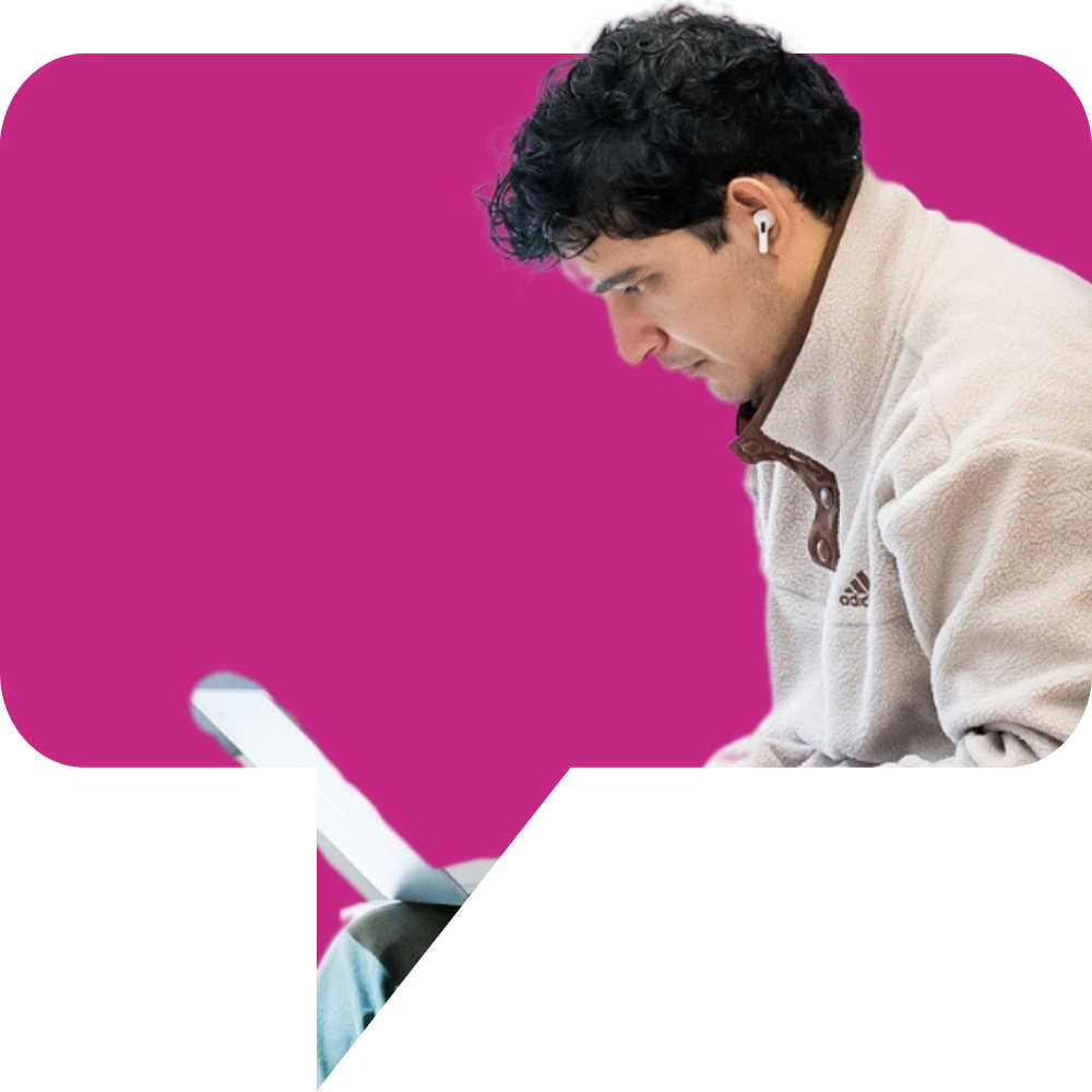 Young man on laptop within a pink speech bubble graphic.