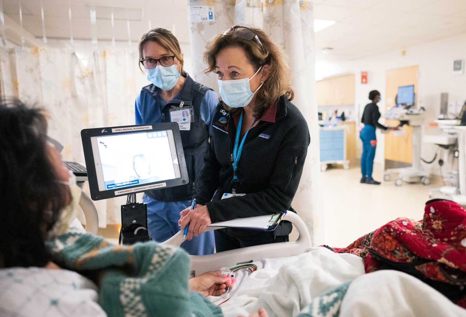 Two nurse practitioners tend to a patient's bedside in an emergency room.