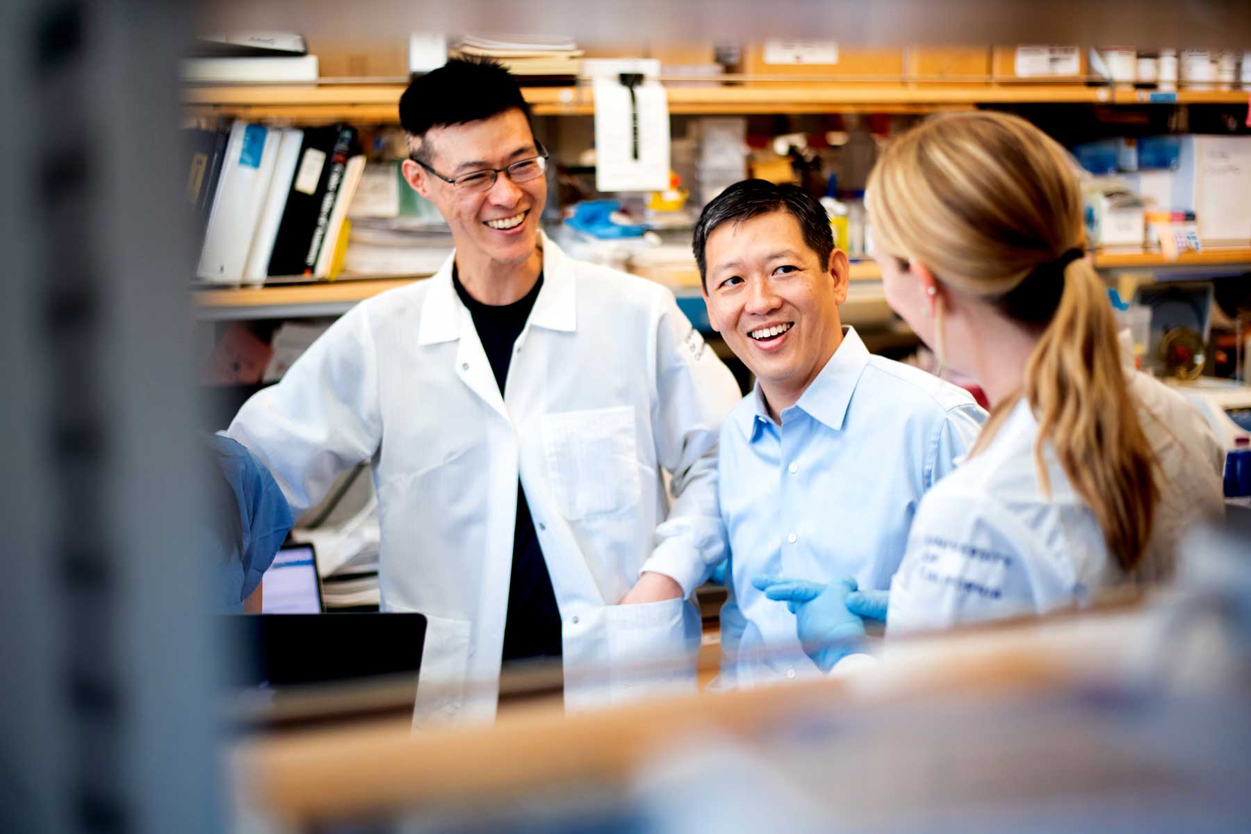 Felix Feng and his colleagues Jonathan Chou and Lisa Chesner smile and discuss together in his lab.