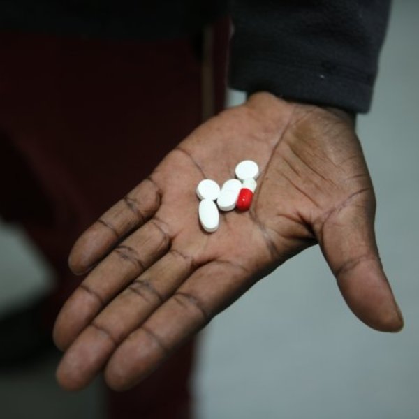 A hand holding a few pills, demonstrating the newer and lower medication regiment to treat tuberculosis.