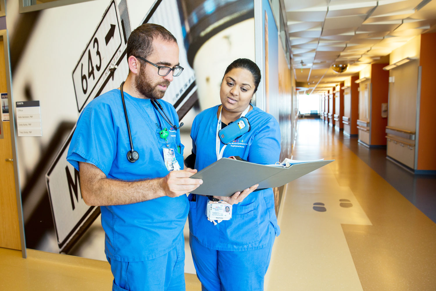 2 UCSF nurses talk in a hospital hallway