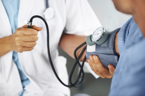 stock image of doctor checking man's blood pressure