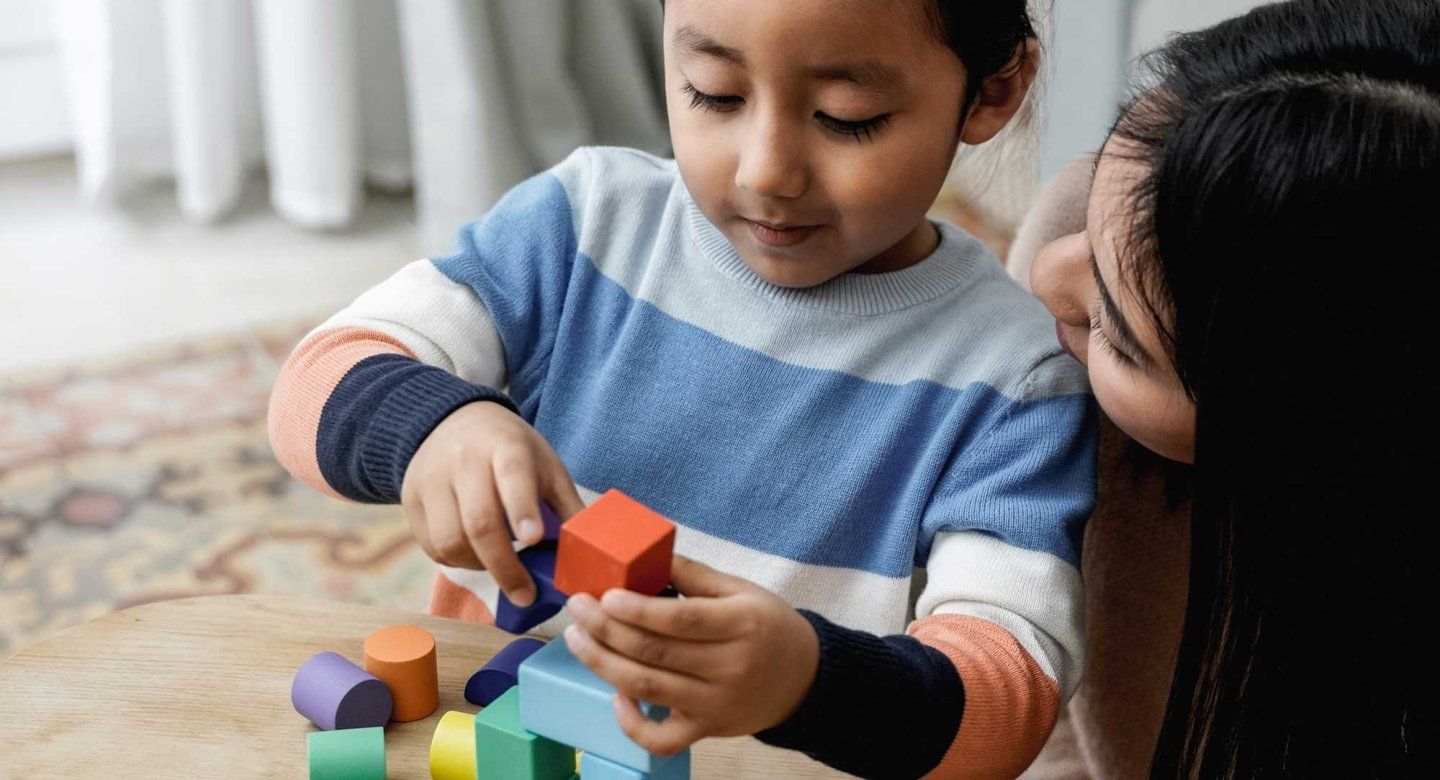 A Latino child and mother play together with toy blocks.