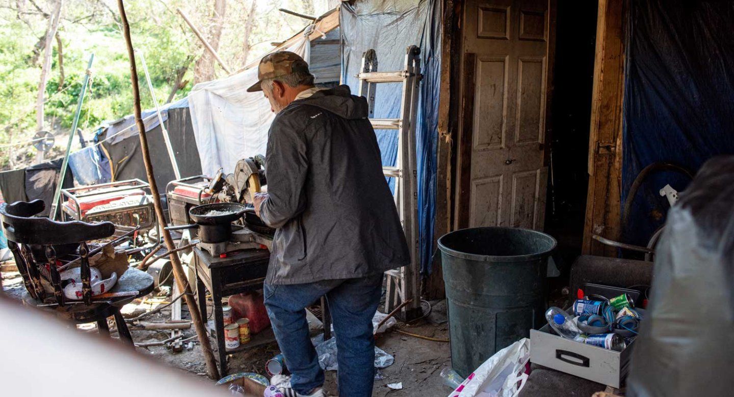 An unhoused man walkes through his encampment.