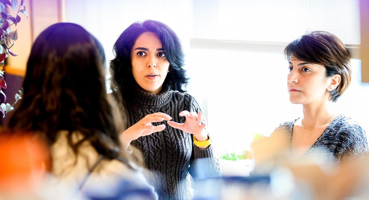 Women in deep conversation look seriously at each other at table.