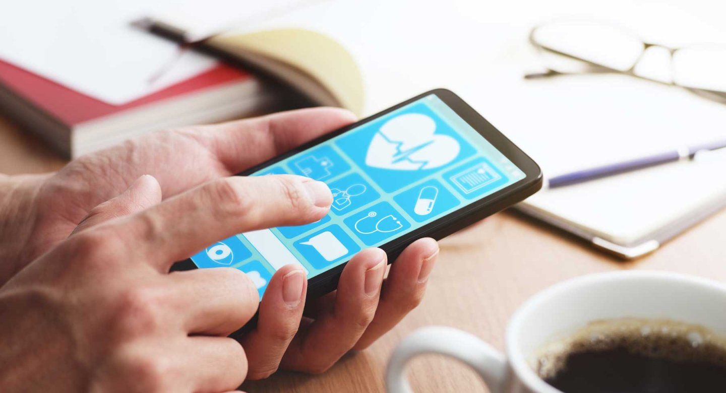 Closeup of male hands touching smartphone screen at table to use digital health applications.