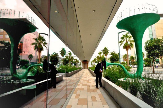 view of green trumpet art sculpture reflected on mirror windows.