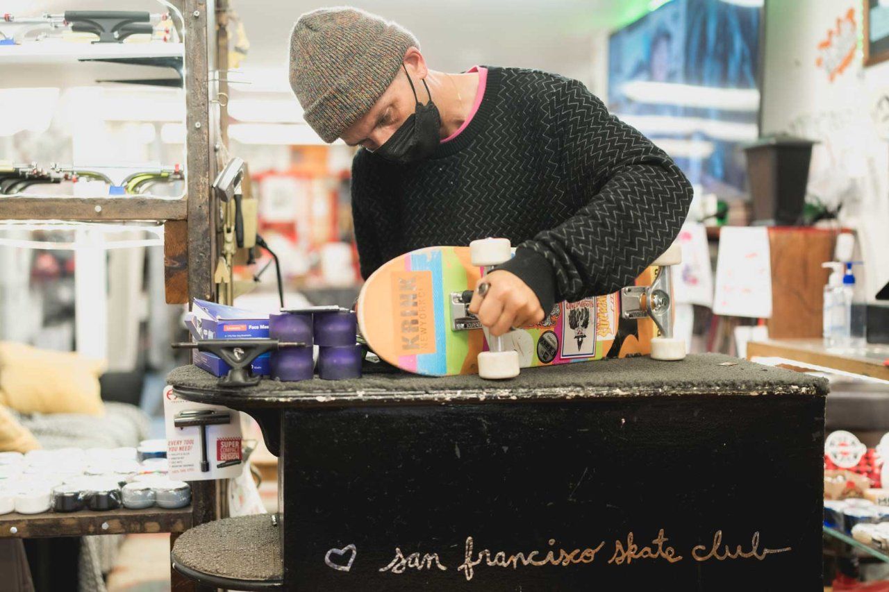 Shawn Connolly installs wheels on a skateboard inside a workshop at the SF Skate Club.