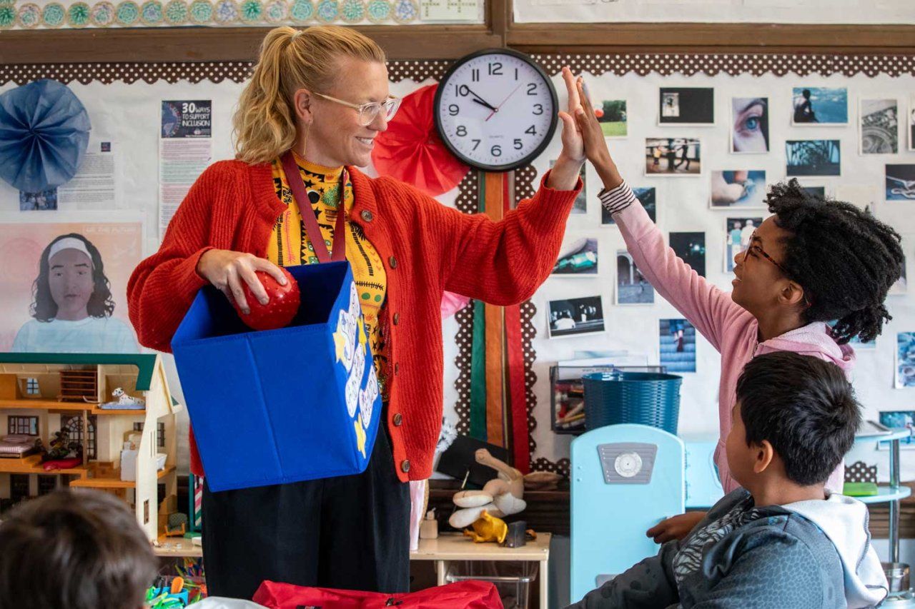 Social worker Jeannette Feddes high fives a student in a classroom.