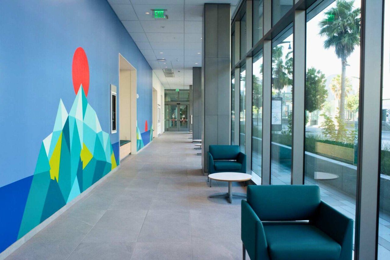 Hallway with large glass windows against the blue and green mural