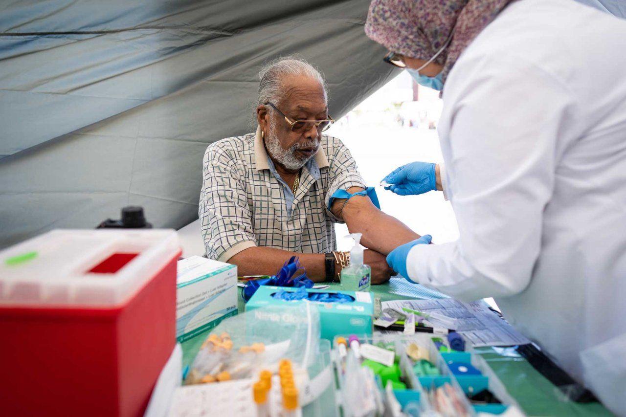 An elderly Black man named Ray Fisher gets a prostate specific antigen test administered by a health practicioner.