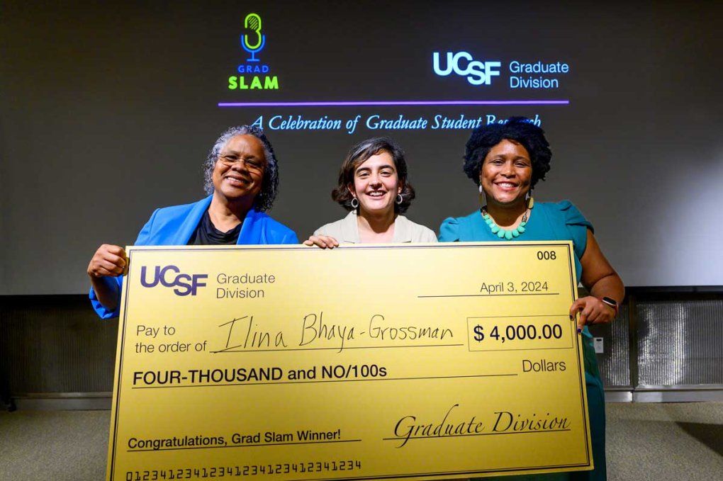 Ilina Bhaya-Grossman, center, holds a ceremonial check after taking first place in Grad Slam 2024 with UCSF Dean of the Graduate Division and Vice Provost Nicquet Blake, PhD, left, and UCSF Assistant Dean for Diversity and Learner Success in the Graduate Division D'Anne Duncan, PhD.