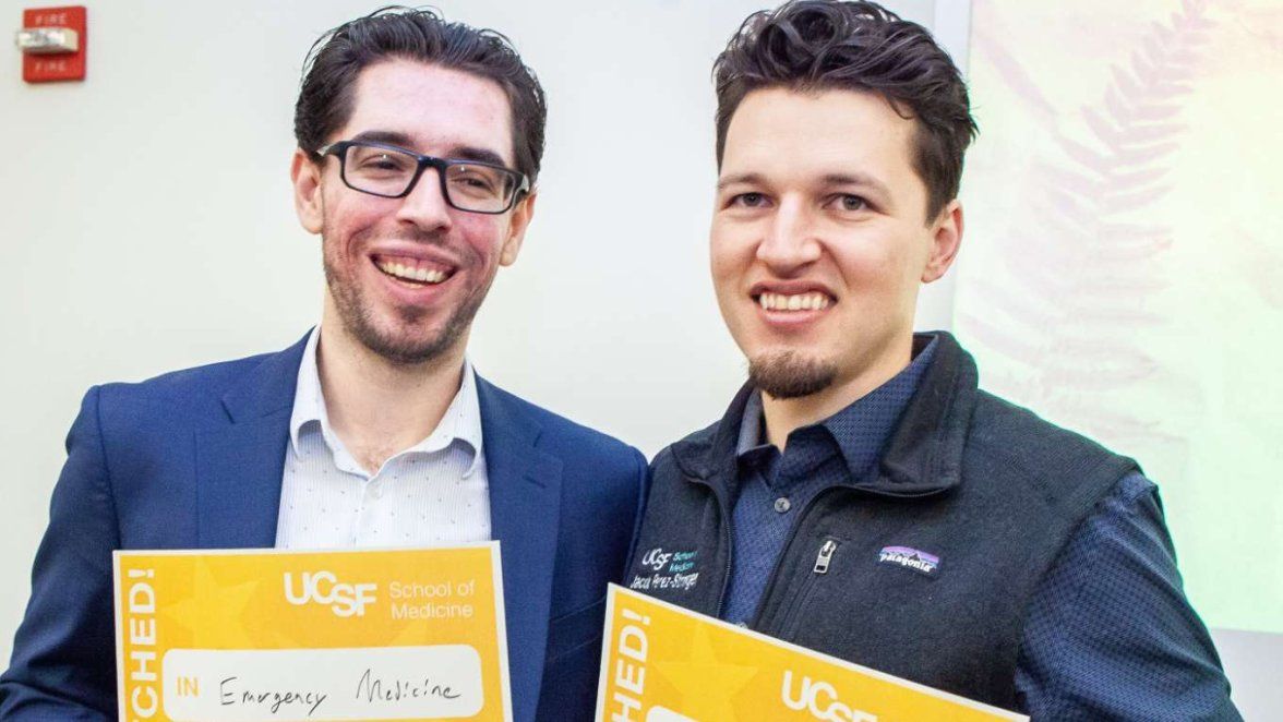 two young men hold up yellow certificates