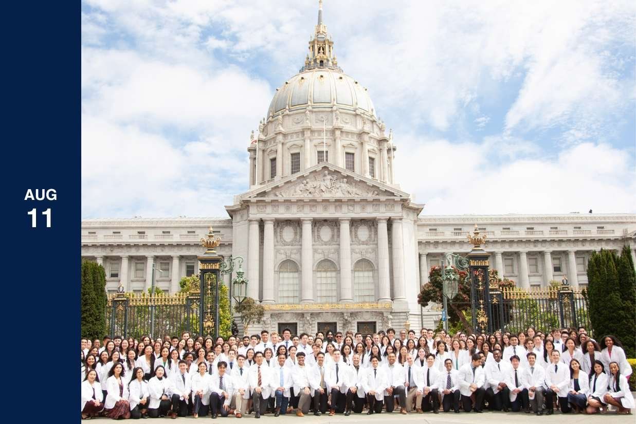 large group of students in white coat in front of city building