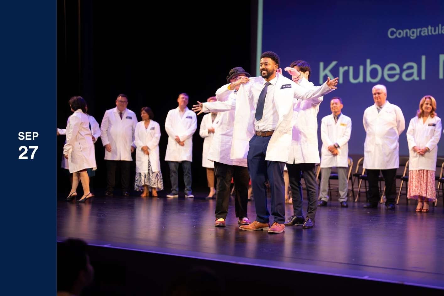 student on stage receives white coat.