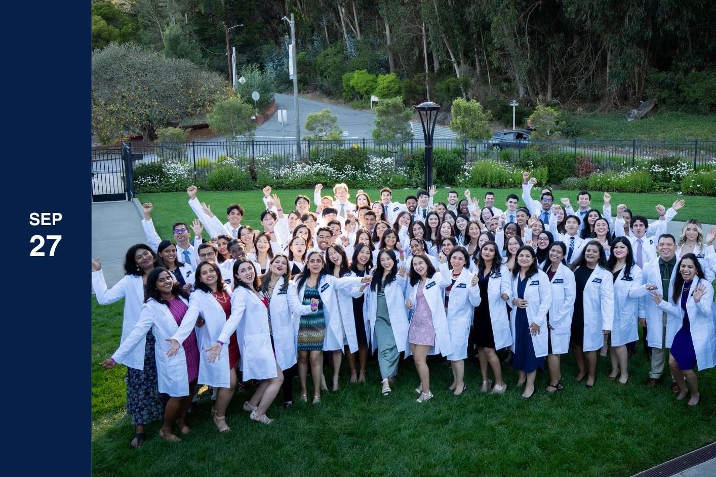 group of students pose in lap coats on grass.