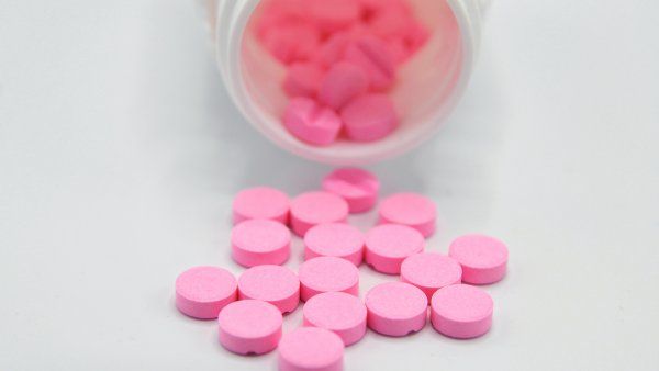 pink pills spilling out of the bottle.
